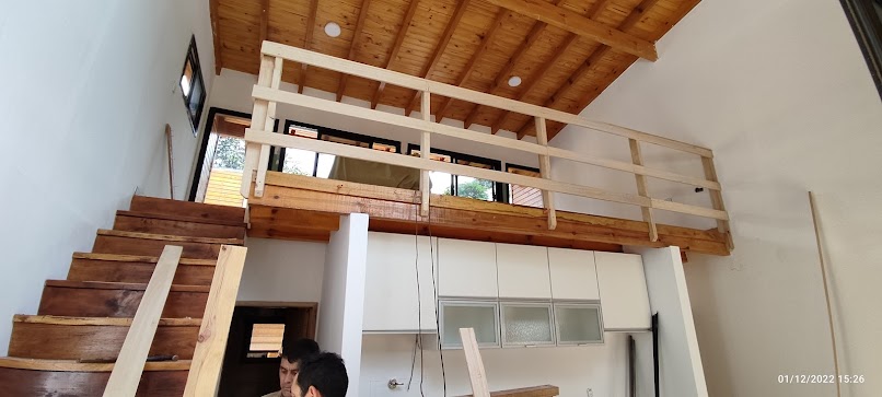 Interior vivienda KIKUE — entrepiso de madera, escalera artesanal y cielo raso a dos aguas